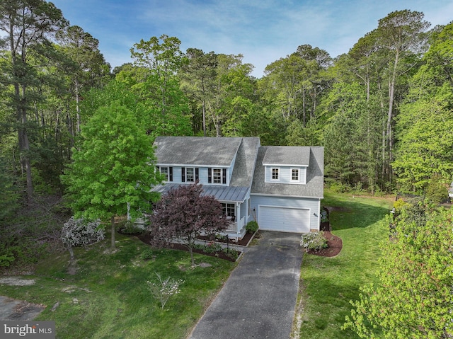 view of front of home featuring a front lawn, an attached garage, a view of trees, driveway, and a porch