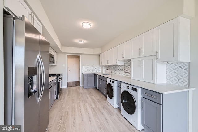 kitchen with stainless steel appliances, light countertops, a sink, light wood-type flooring, and white cabinetry