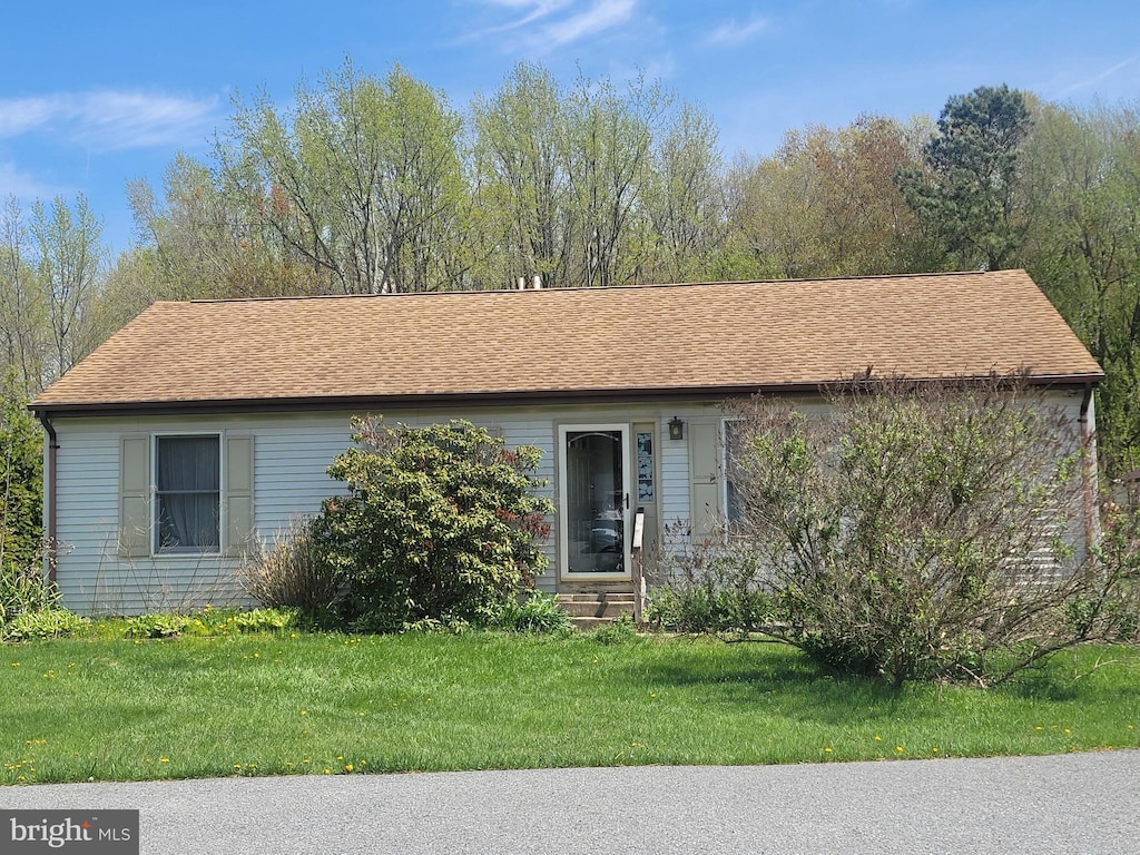 ranch-style house featuring a shingled roof, entry steps, and a front yard