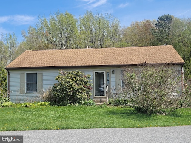ranch-style house featuring a shingled roof, entry steps, and a front yard