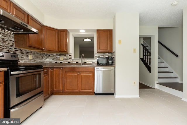 19320 Liberty Heights Ln, Germantown, MD 20874 - kitchen featuring appliances with stainless steel finishes, ventilation hood, tasteful backsplash, brown cabinets, and a textured ceiling