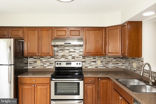 19320 Liberty Heights Ln, Germantown, MD 20874 - kitchen with under cabinet range hood, appliances with stainless steel finishes, dark countertops, brown cabinetry, and a textured ceiling