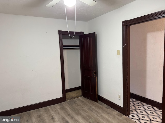 unfurnished bedroom with wood finished floors, baseboards, a ceiling fan, and a closet