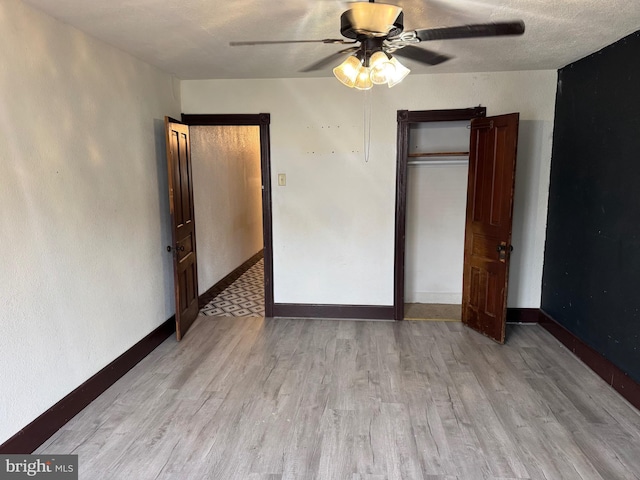 unfurnished bedroom featuring wood finished floors, baseboards, ceiling fan, and a closet