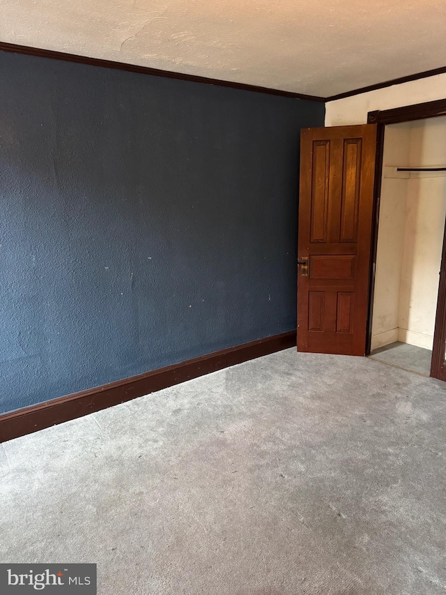 unfurnished bedroom with carpet flooring, baseboards, ornamental molding, and a closet