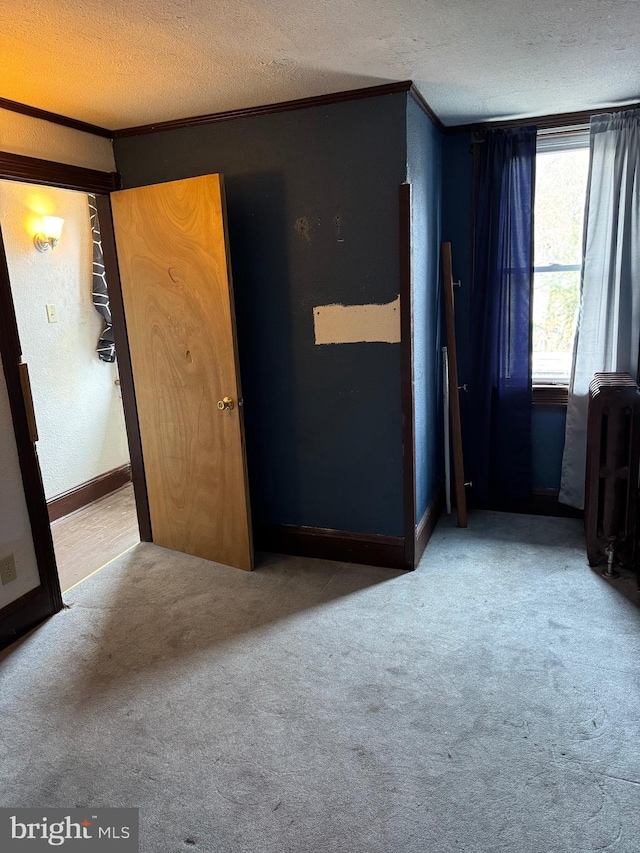 unfurnished bedroom with ornamental molding, carpet flooring, a textured ceiling, and baseboards