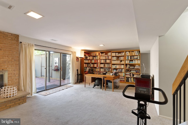 carpeted office featuring a brick fireplace and visible vents