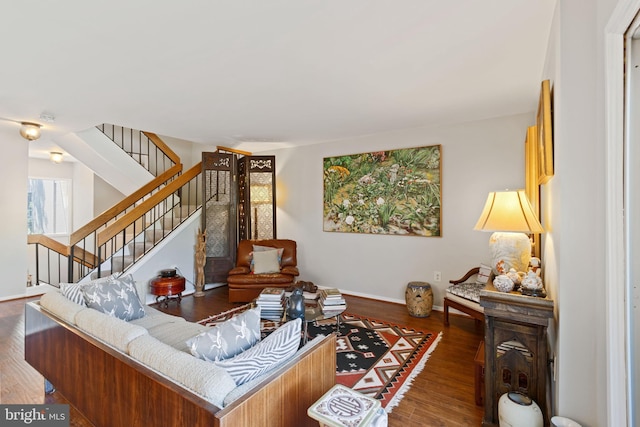 living area with baseboards, wood finished floors, and stairway