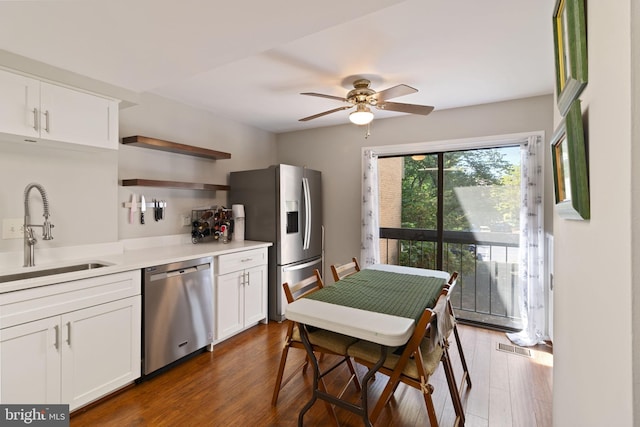 kitchen with white cabinets, open shelves, appliances with stainless steel finishes, a sink, and dark wood-style floors