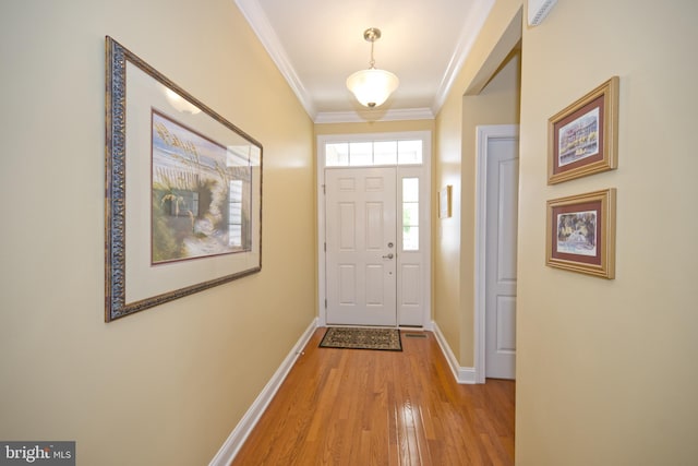 doorway featuring baseboards, ornamental molding, and light wood finished floors