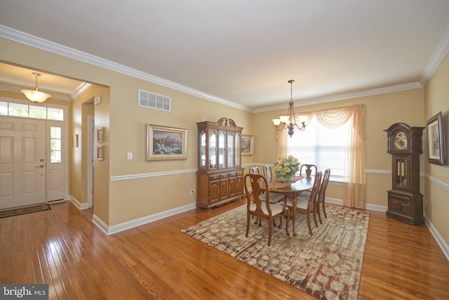 dining room with an inviting chandelier, wood finished floors, visible vents, and crown molding
