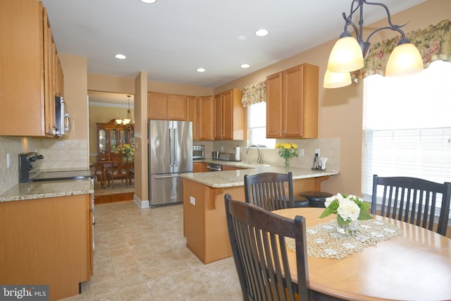kitchen featuring stainless steel appliances, backsplash, a peninsula, and a sink