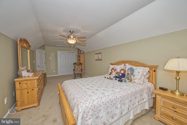 bedroom featuring light colored carpet, a closet, vaulted ceiling, baseboards, and a ceiling fan