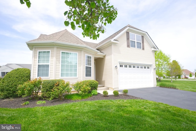 view of front of home featuring roof with shingles, aphalt driveway, a front lawn, and an attached garage