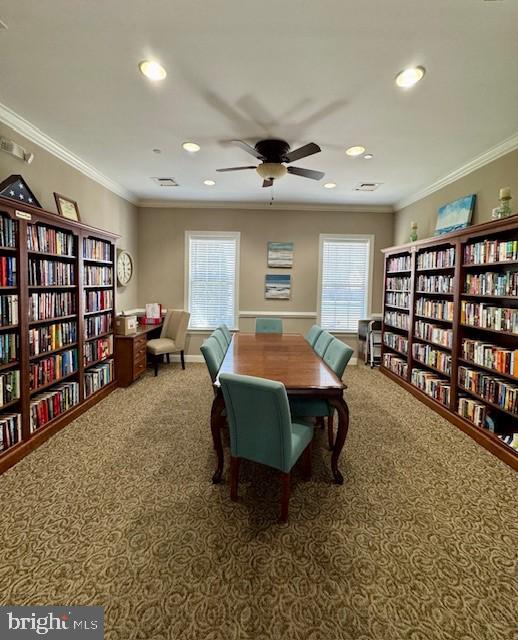 sitting room featuring carpet flooring, a ceiling fan, bookshelves, and a healthy amount of sunlight