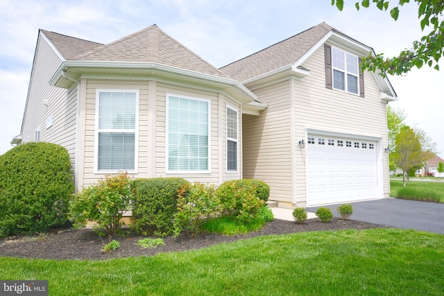view of front of property with aphalt driveway, a shingled roof, a front yard, and an attached garage
