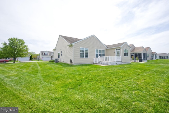 back of property with a lawn, a deck, and central AC unit