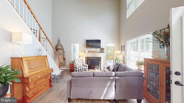 43295 Ardmore St, Ashburn, VA 20147 - living area with light wood-type flooring, a glass covered fireplace, a towering ceiling, and stairs