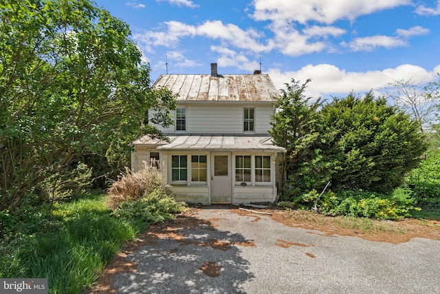 traditional home featuring metal roof, a chimney, and a standing seam roof