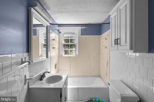 bathroom featuring bathtub / shower combination, vanity, a textured ceiling, tile walls, and tasteful backsplash