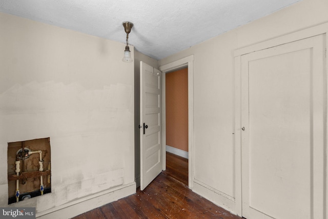 unfurnished bedroom featuring baseboards, a textured ceiling, dark wood finished floors, and a closet
