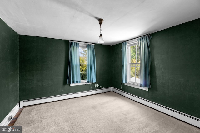 carpeted spare room with baseboards, a baseboard heating unit, and plenty of natural light