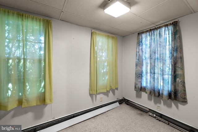 empty room with baseboard heating and a paneled ceiling