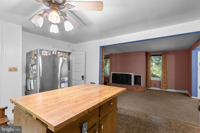 kitchen featuring a kitchen island, a ceiling fan, freestanding refrigerator, dark carpet, and butcher block countertops