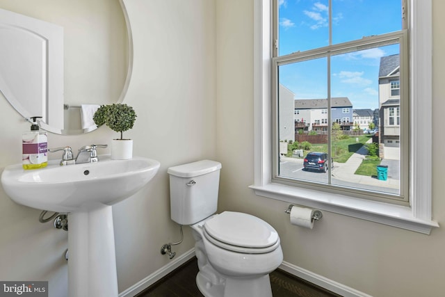 bathroom featuring toilet, baseboards, and a sink