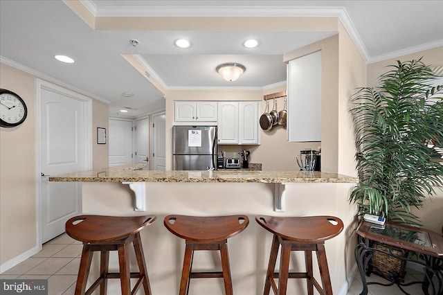 4201 Coastal Hwy Unit 116, Ocean City, MD 21842 - kitchen featuring white cabinets, freestanding refrigerator, baseboards, a peninsula, and a breakfast bar area
