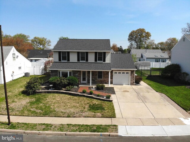 traditional-style house featuring a porch, a front lawn, driveway, an attached garage, and fence