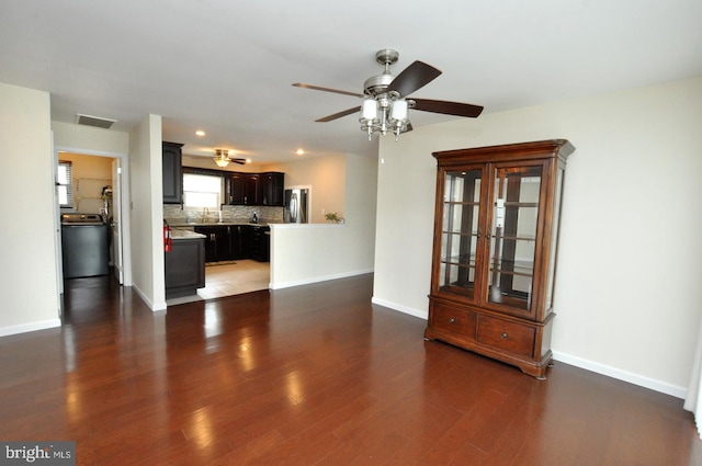 unfurnished living room with visible vents, a ceiling fan, baseboards, and wood finished floors