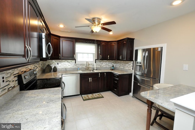 kitchen with decorative backsplash, a sink, dark brown cabinetry, a ceiling fan, and appliances with stainless steel finishes
