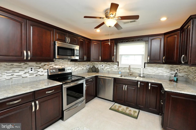 kitchen with visible vents, light stone countertops, ceiling fan, a sink, and appliances with stainless steel finishes