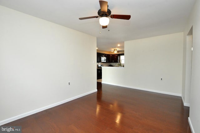unfurnished living room featuring ceiling fan, dark wood finished floors, and baseboards