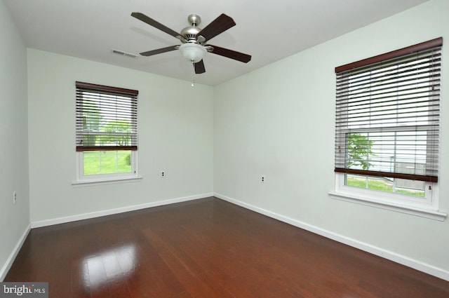 spare room featuring baseboards, visible vents, ceiling fan, and dark wood-type flooring