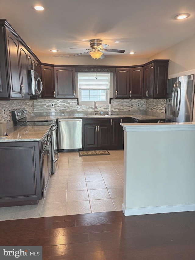 kitchen featuring decorative backsplash, a sink, dark brown cabinets, a ceiling fan, and appliances with stainless steel finishes