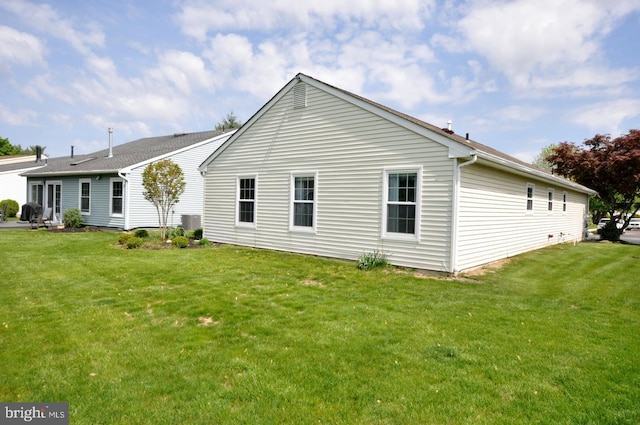 back of property with central air condition unit and a yard