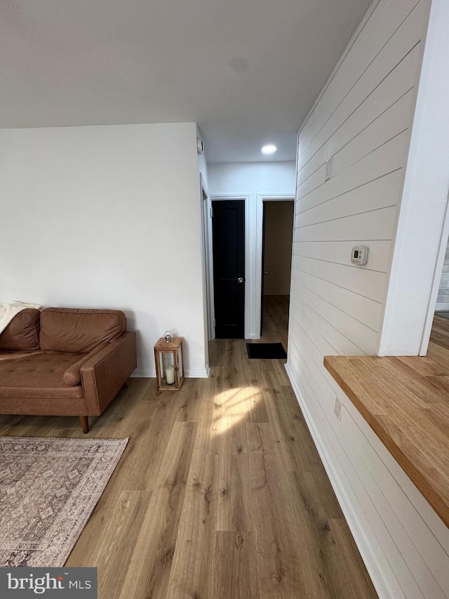 hall featuring wood finished floors, wood walls, and baseboards