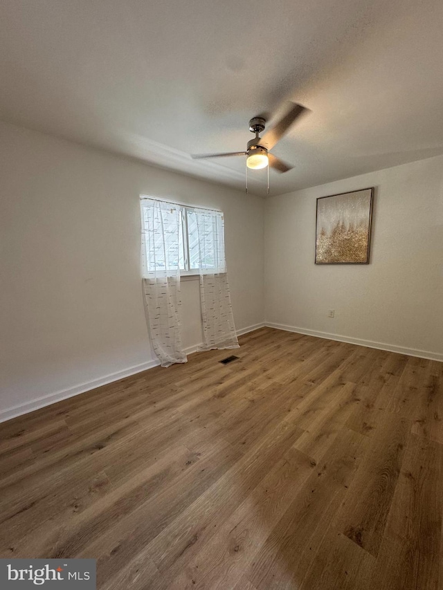 empty room featuring ceiling fan, wood finished floors, and baseboards
