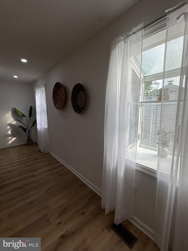 hallway featuring wood finished floors, baseboards, and recessed lighting