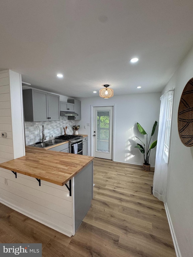 kitchen with wooden counters, double oven range, a sink, gray cabinets, and decorative backsplash