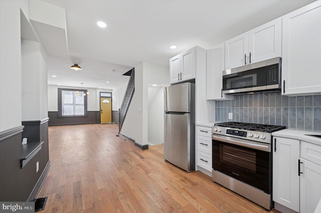 2931 W Susquehanna Ave, Philadelphia, PA 19121 - kitchen featuring tasteful backsplash, light countertops, stainless steel appliances, light wood-style flooring, and white cabinetry