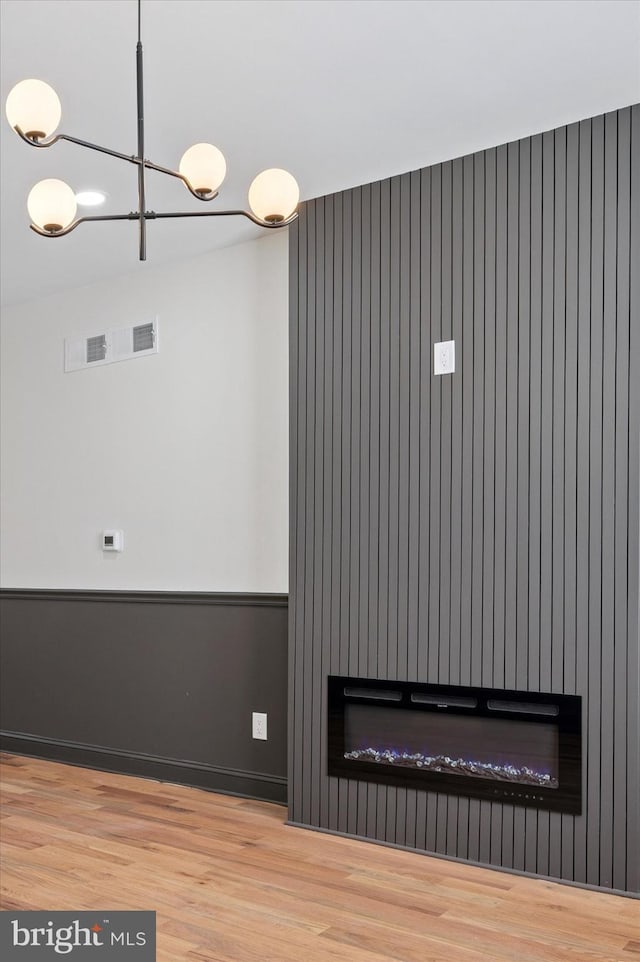 2931 W Susquehanna Ave, Philadelphia, PA 19121 - interior space featuring a glass covered fireplace, wood finished floors, visible vents, and a notable chandelier