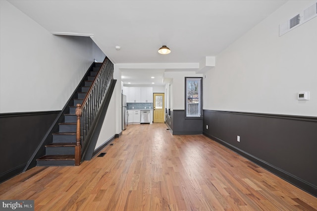 2931 W Susquehanna Ave, Philadelphia, PA 19121 - unfurnished living room featuring baseboards, light wood-style flooring, visible vents, and stairway