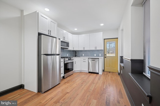 2931 W Susquehanna Ave, Philadelphia, PA 19121 - kitchen with a sink, decorative backsplash, light wood-style floors, stainless steel appliances, and white cabinets