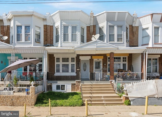multi unit property featuring covered porch and brick siding