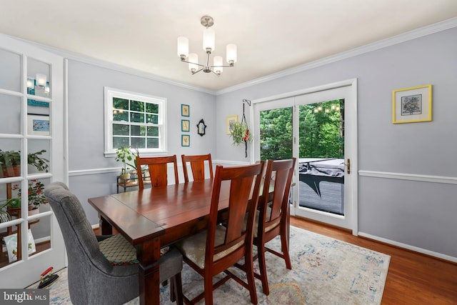 dining room featuring ornamental molding, a chandelier, plenty of natural light, and wood finished floors