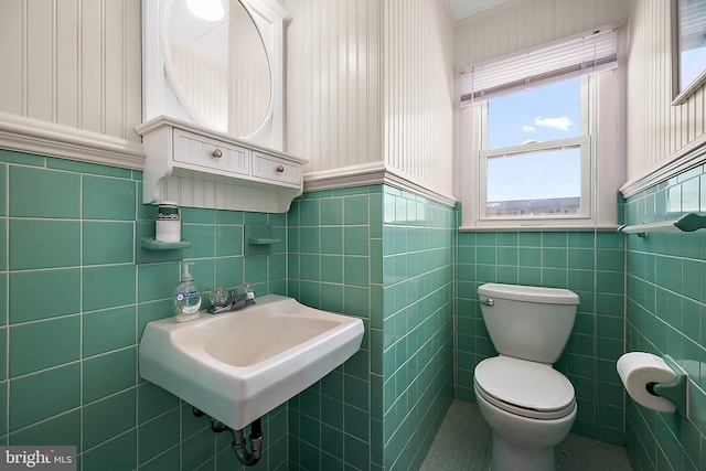 12506 Assawoman Dr, Ocean City, MD 21842 - half bathroom featuring toilet, a wainscoted wall, a sink, and tile walls