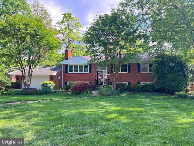 split foyer home with a front yard, brick siding, and a chimney